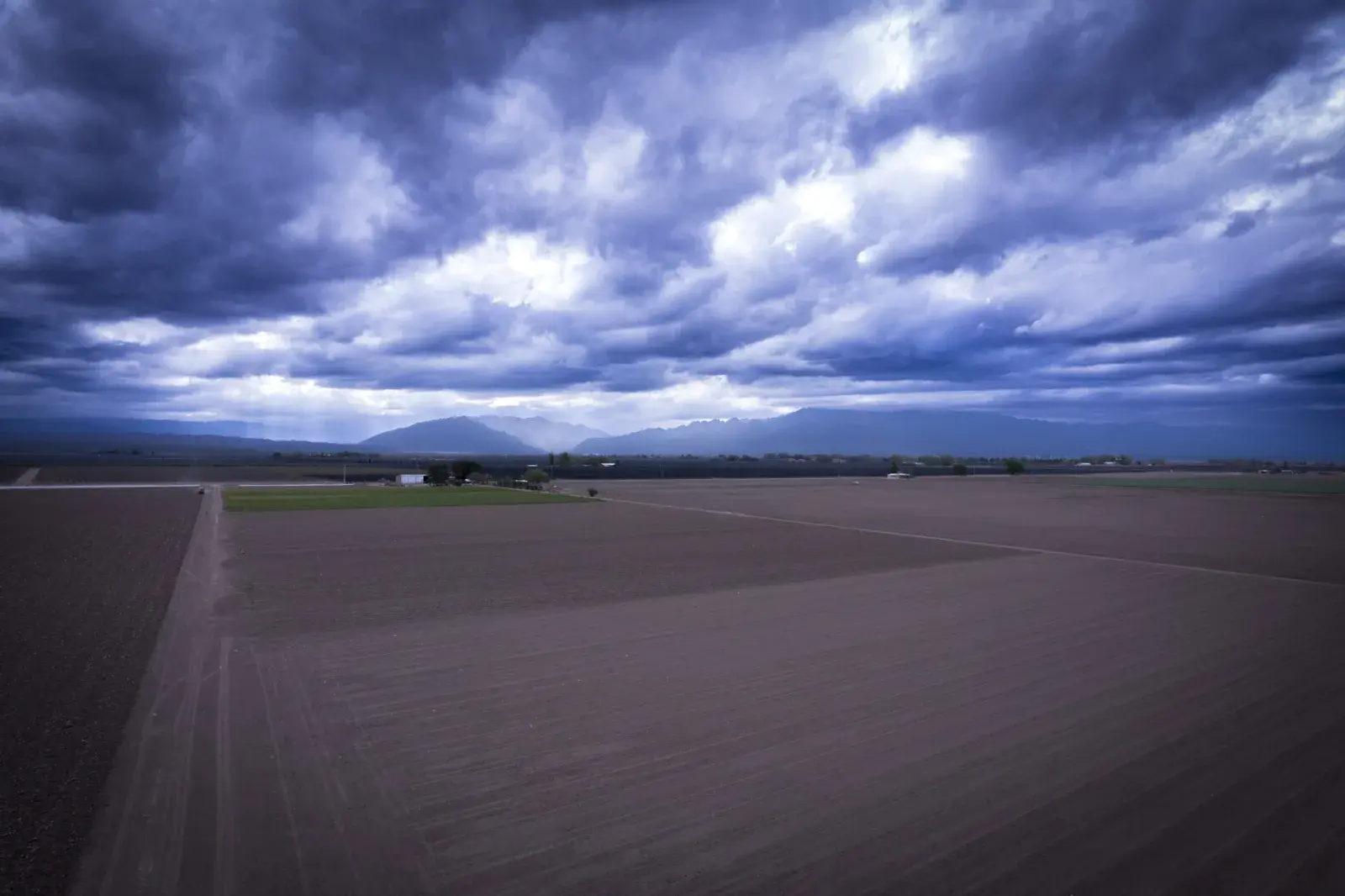 Vista aérea de campos cultivados de Mendoza con la cordillera de los Andes al fondo y cielo de tormenta